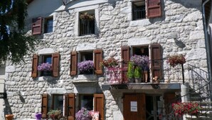 Un bâtiment en pierre doté de nombreuses fenêtres, dont certaines sont pourvues de volets, et de balcons ornés de jardinières.
