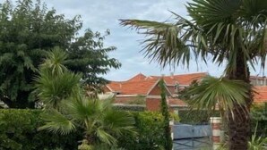 A wooden deck with a pathway leading to a building with red-tiled roofs. - Veritable Soulacaise a 10 Mètres de la Plage (Soulac-sur-Mer)