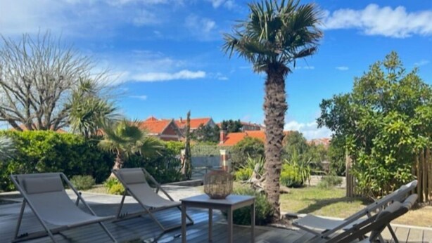 A wooden deck with lounge chairs and a palm tree. - Veritable Soulacaise a 10 Mètres de la Plage (Soulac-sur-Mer)