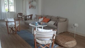 A living room with a sofa, two armchairs, a coffee table, and a rug. - Veritable Soulacaise a 10 Mètres de la Plage (Soulac-sur-Mer)