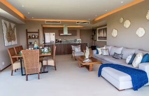 Una sala de estar moderna con comedor, una cocina al fondo y un sofá con una manta azul.