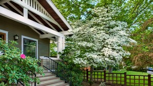 A house with a porch, a staircase, a fence, and a tree with white flowers. - A Cowslip's Belle Inn (Ashland)