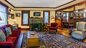 A traditional living room with a fireplace, red sofas, a coffee table, and a patterned rug. - A Cowslip's Belle Inn (Ashland)