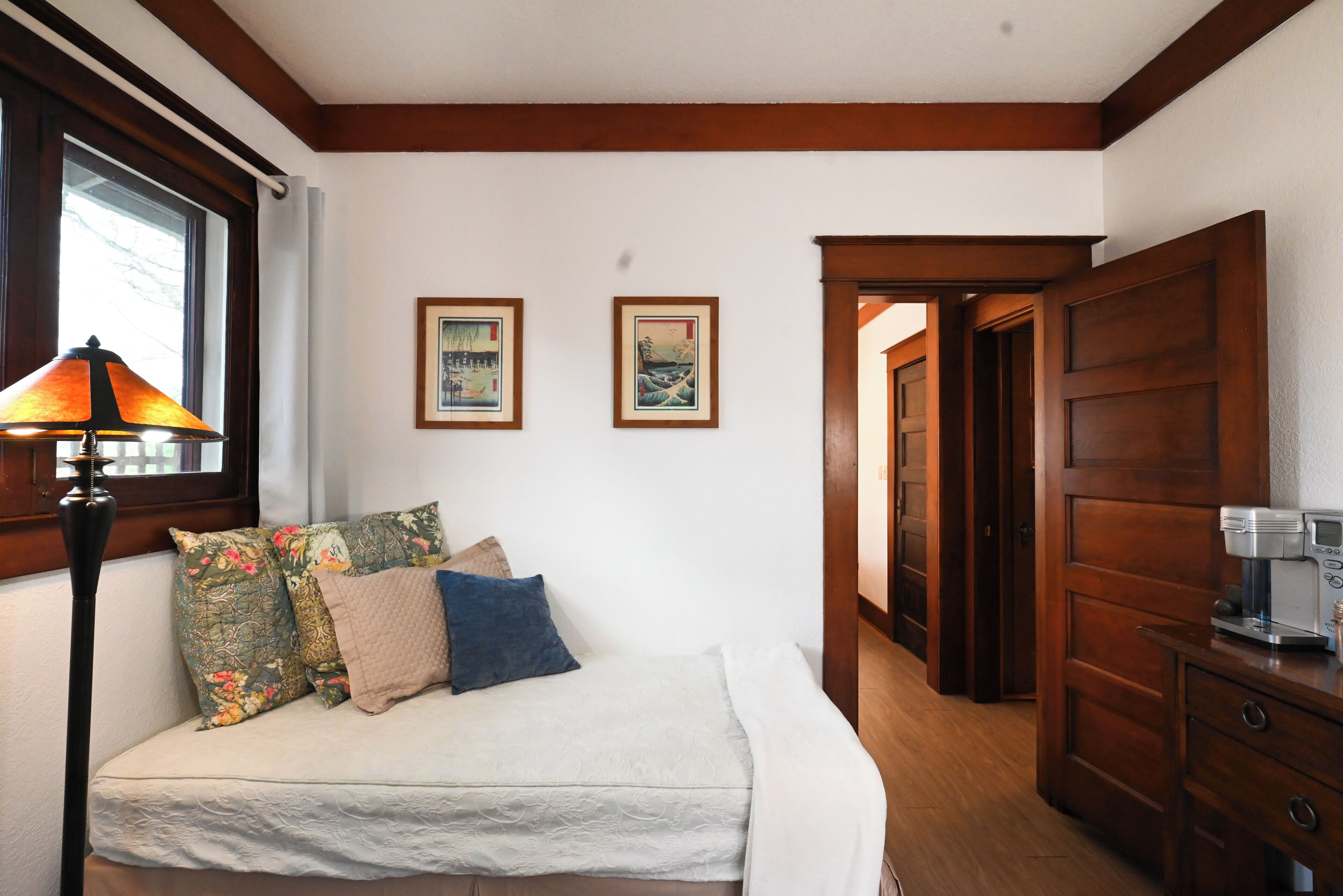 A bedroom with a bed, pillows, a lamp, and two framed pictures on the wall.