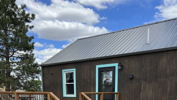 A building with a wooden deck, a staircase, and a small garden area. - Whispering Wind Cabin where peacefulness and relaxation surrounds you (Pfeifer)