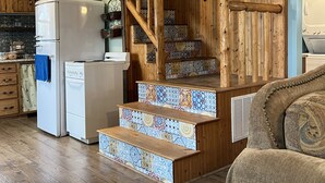 A kitchen with a refrigerator, oven, and wooden staircase leading to a loft area. - Whispering Wind Cabin where peacefulness and relaxation surrounds you (Pfeifer)