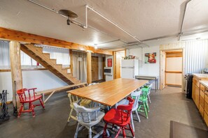 A spacious kitchen with a large wooden table, colorful chairs, a refrigerator, and a staircase leading to another level. - Farm Retreat Apartment & 2 Cabins near rustic hot springs (Whitehall)