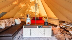 A cozy tent interior with a sofa, a coffee table, and a dining area.
