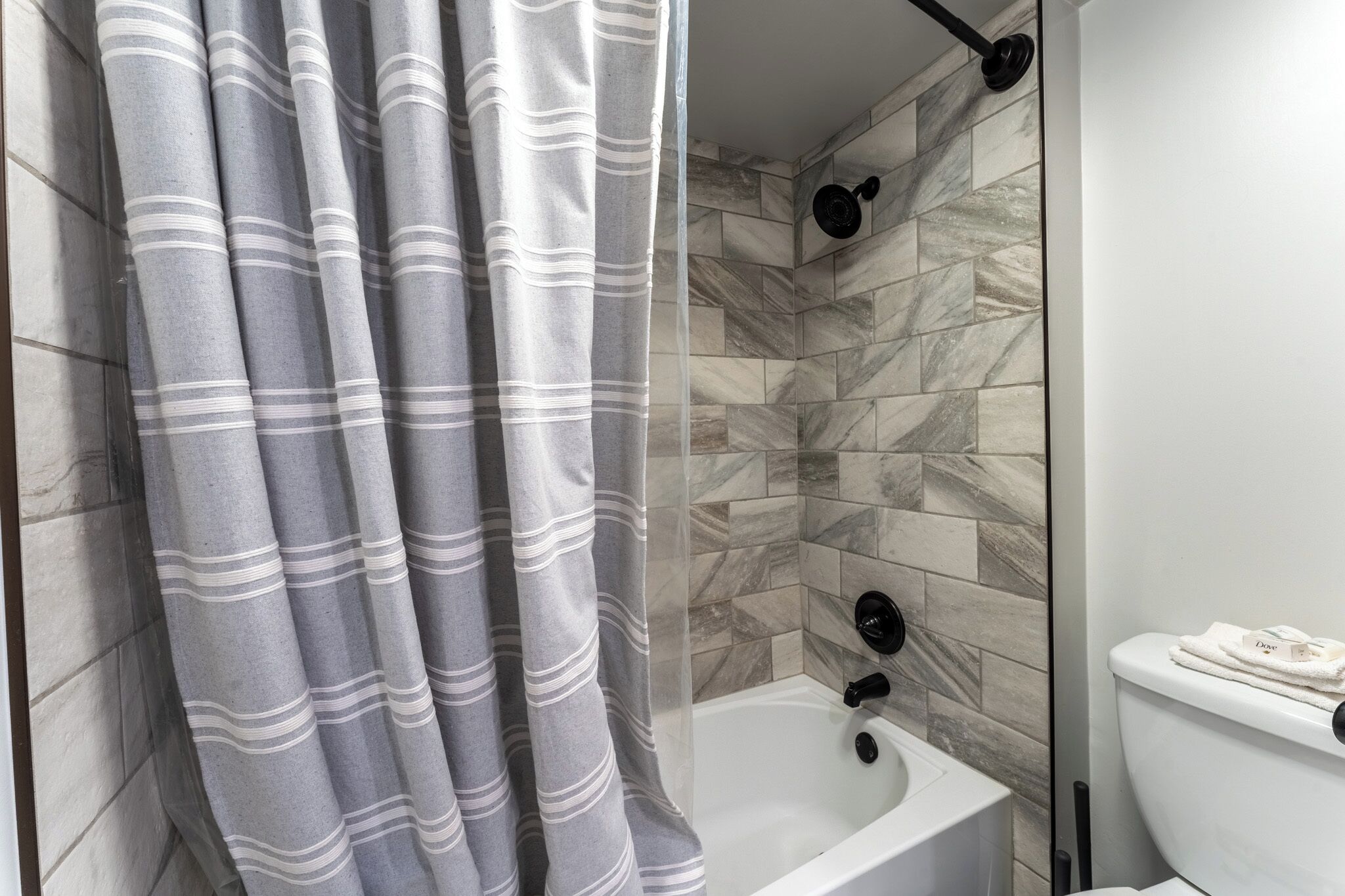 Un baño moderno con cortina de ducha, bañera y retrete.