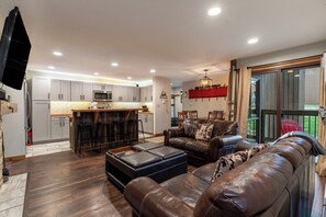 A modern kitchen with grey cabinets, a central island, and a flat-screen TV mounted on the wall.