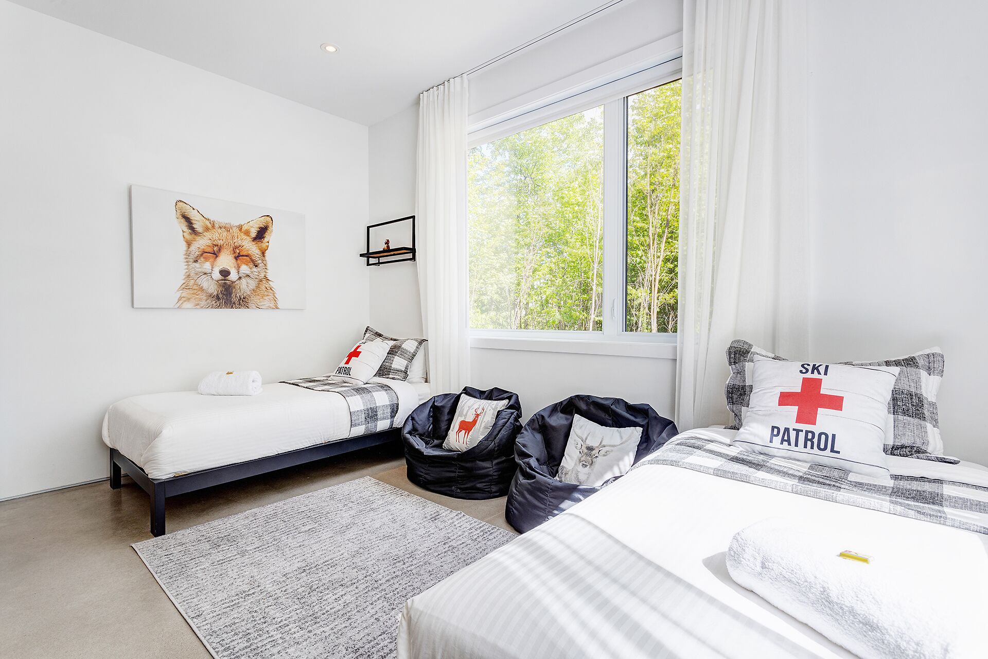 A bedroom with two beds, a window with curtains, a framed animal picture, and a small shelf with a figurine.