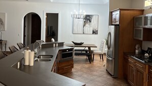 Una cocina moderna con una isla central, electrodomésticos integrados y un comedor con candelabro.