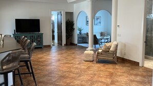 Amplia sala de estar con un televisor grande, una mesa de comedor y asientos cómodos.