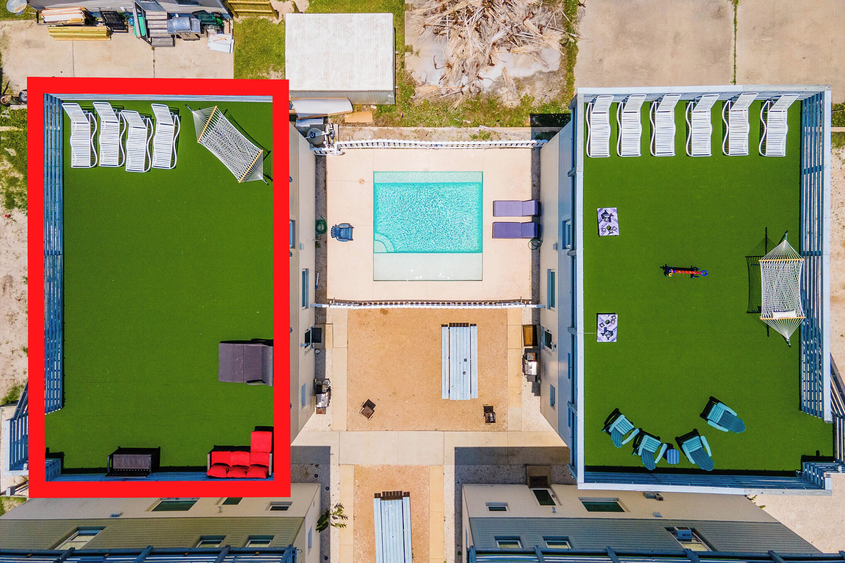 An aerial view of a hotel with a swimming pool, multiple lounge areas, and a parking lot.