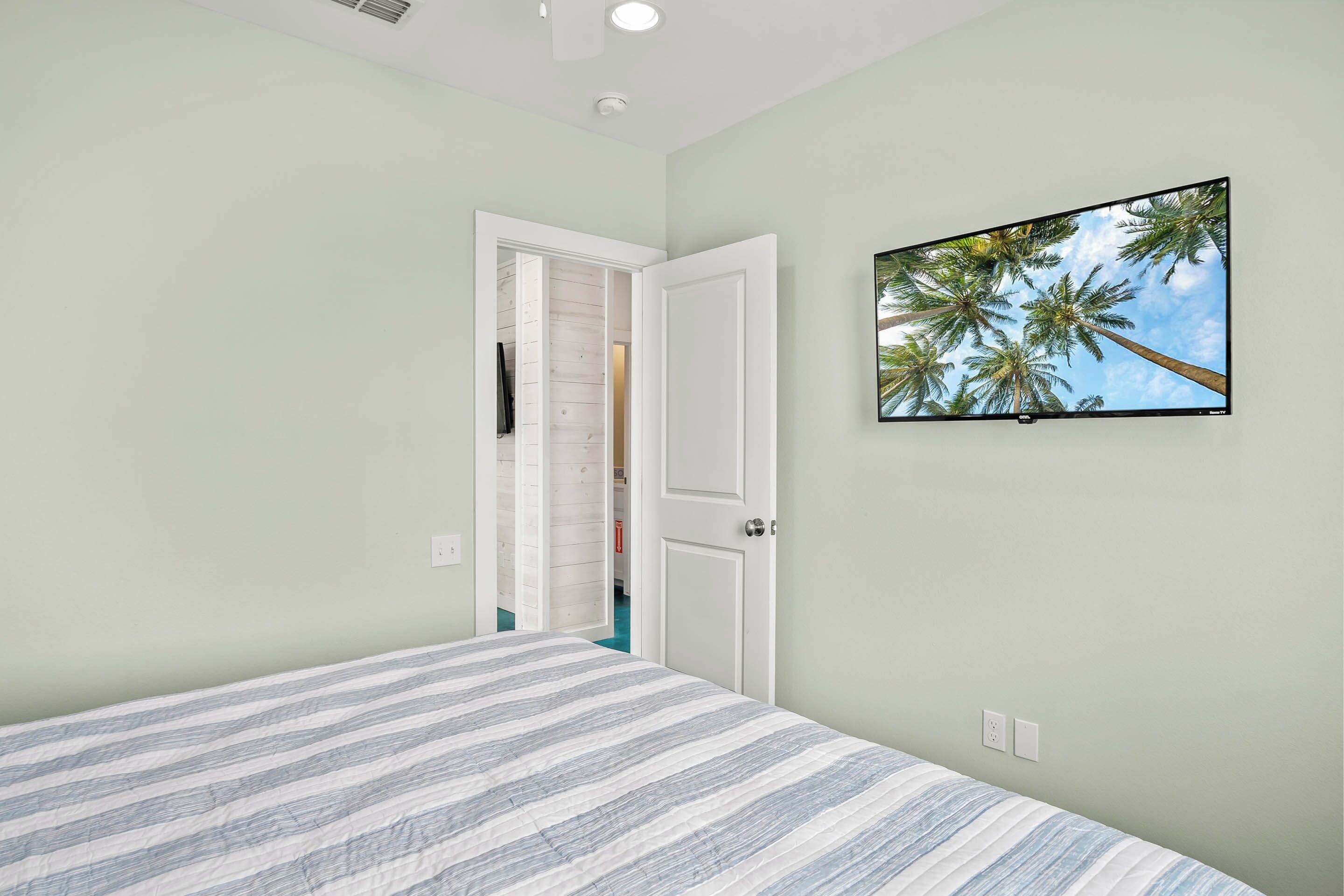 A bedroom with a bed, a door leading to a closet, and a TV on the wall.
