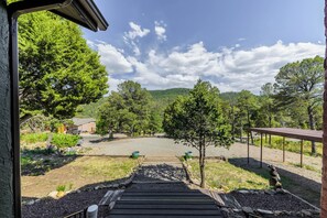 A view of a driveway leading to a house with a covered porch, surrounded by trees and a mountain in the background. - Castle House by Ruidoso Vacation Rentals (Ruidoso)