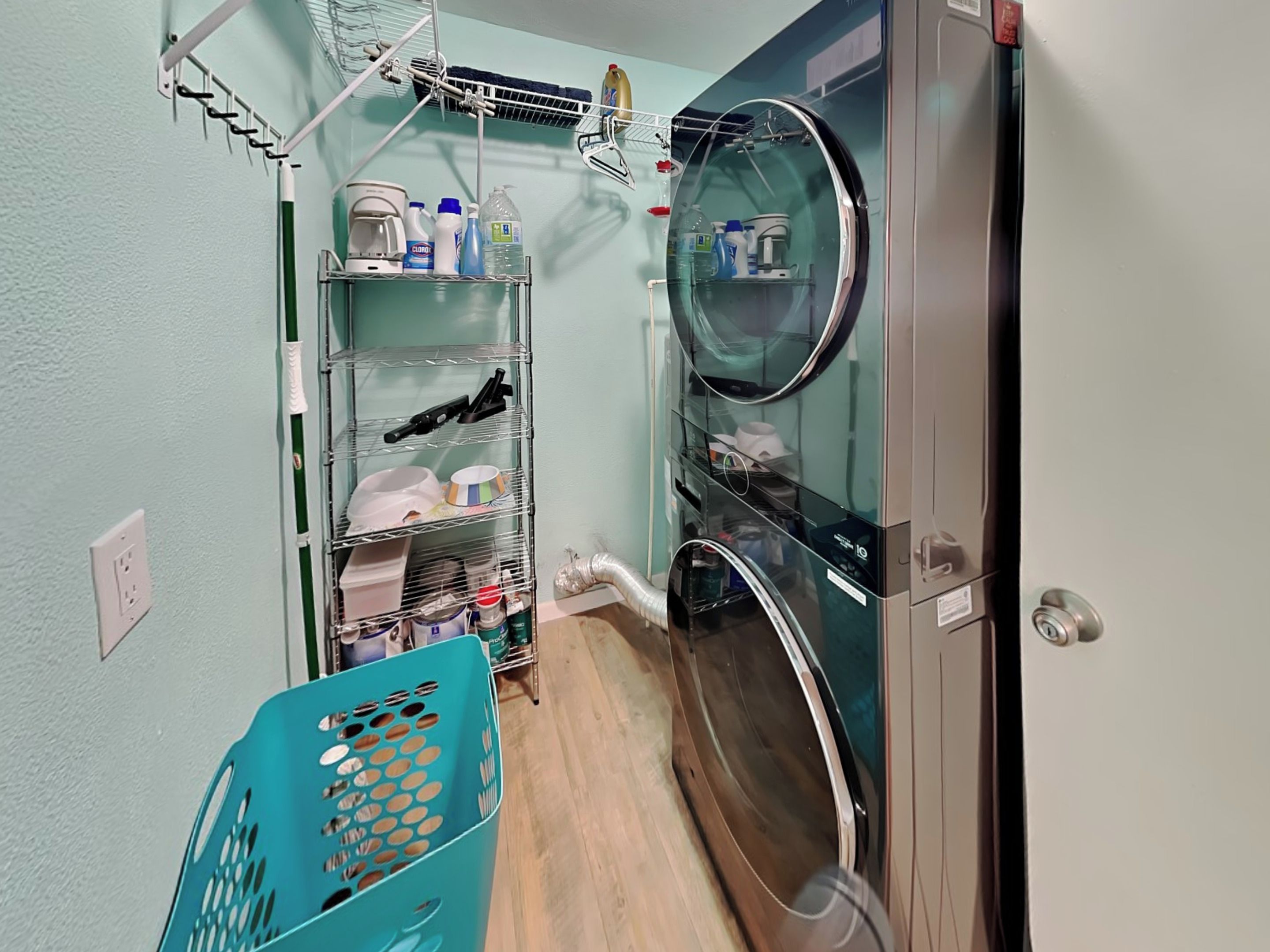 A laundry room with a washing machine, dryer, and shelves with cleaning supplies.