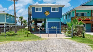 A two-story building with a blue exterior and a sun emblem on the front. - Sand Piper by Miss Kitty’s (Rockport)