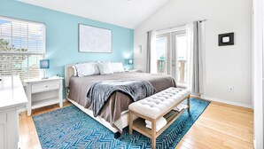 A bedroom with a bed, a bench, a desk, and a window. - The Salty Sandpiper by Silver Sands Vacation Rentals (Port Aransas)