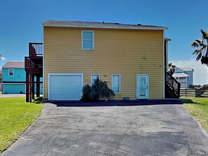 A two-story building with a garage, a small porch, and a well-maintained lawn. - The Salty Sandpiper by Silver Sands Vacation Rentals (Port Aransas)