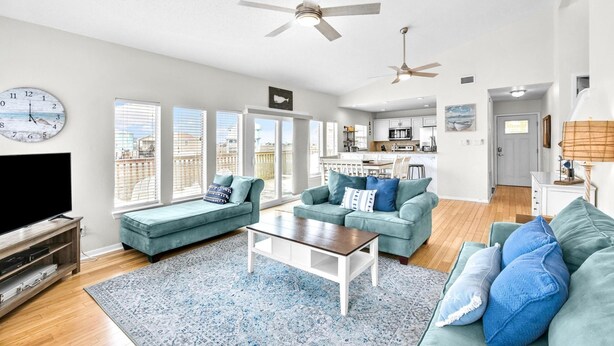 A spacious living room with a large TV, two sofas, a coffee table, and a kitchen in the background. - The Salty Sandpiper by Silver Sands Vacation Rentals (Port Aransas)