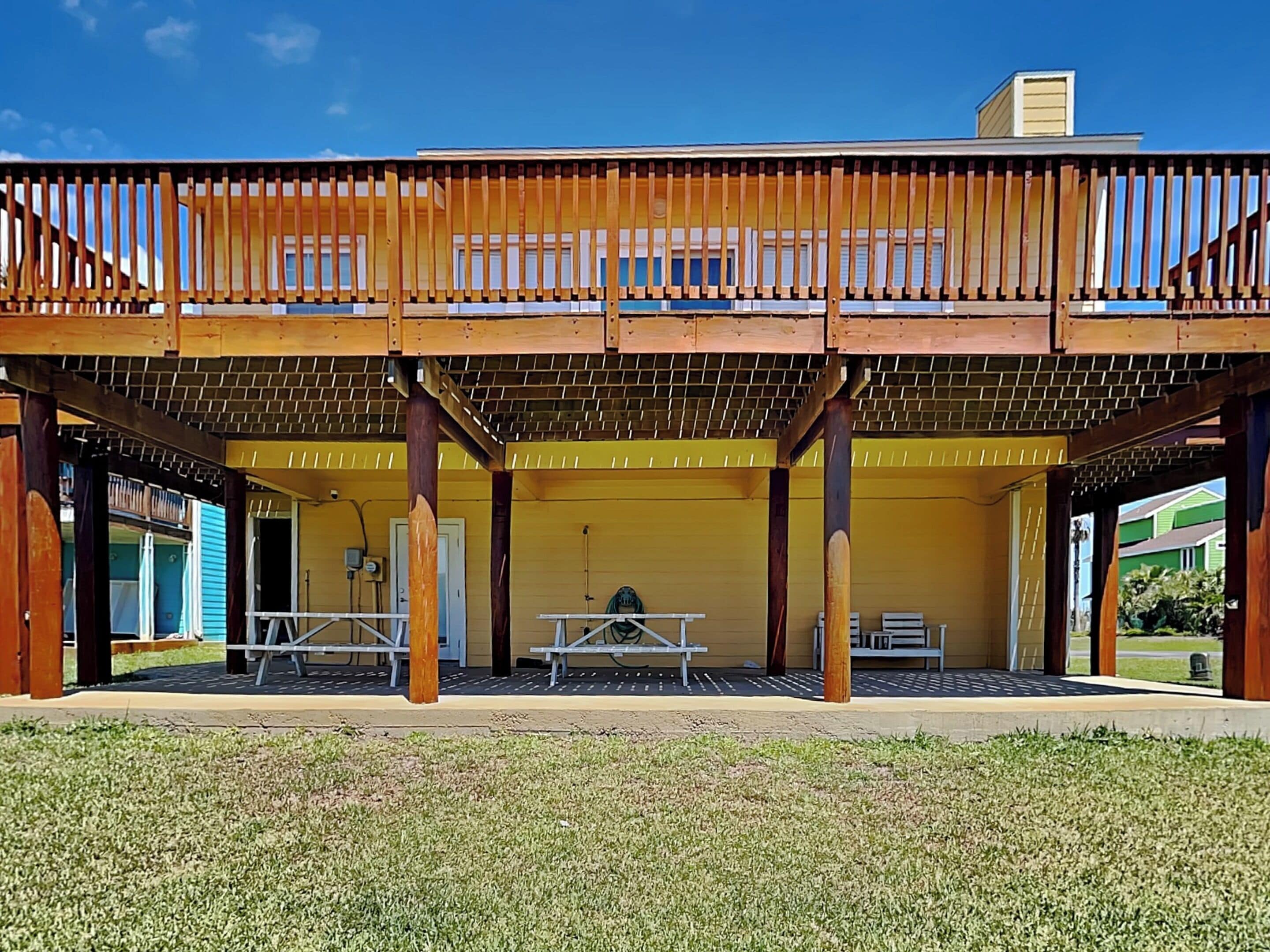 Un espacio al aire libre cubierto con una terraza de madera, mesas y bancos.