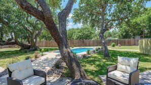 A backyard with a swimming pool, two wicker chairs, and a grill. - Reel Blessing by Miss Kitty’s (Rockport)