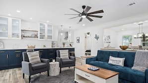 Un salon moderne avec un canapé bleu foncé, des fauteuils gris et une table basse en bois.