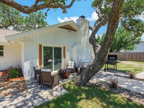 A house with a patio area featuring outdoor furniture, a grill, and a tree. - Reel Blessing by Miss Kitty’s (Rockport)