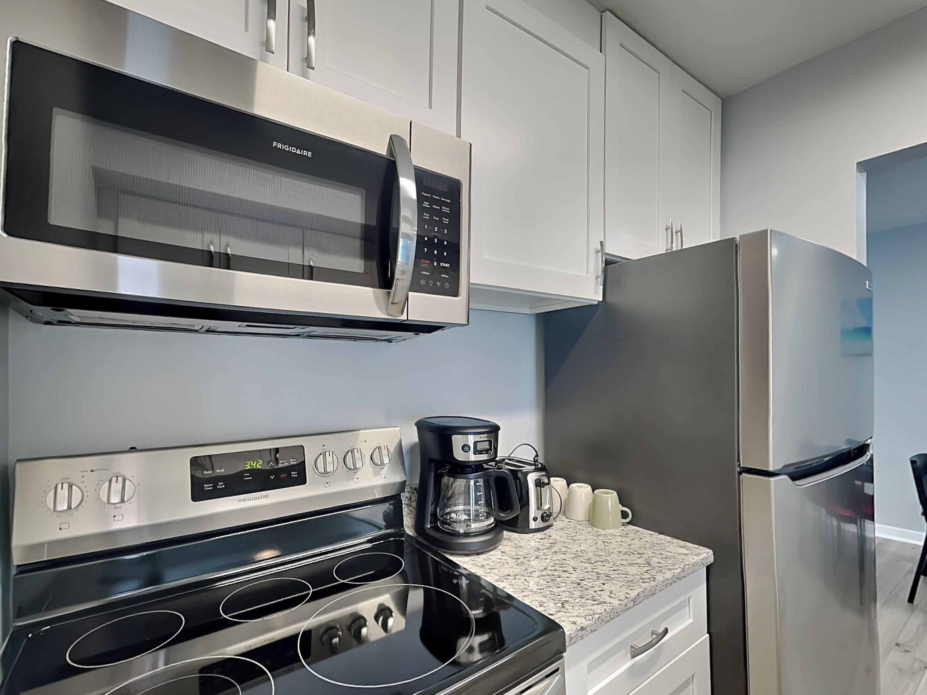 Una cocina con microondas, horno y refrigerador de acero inoxidable.