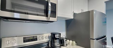 Una cocina con microondas, horno y refrigerador de acero inoxidable.