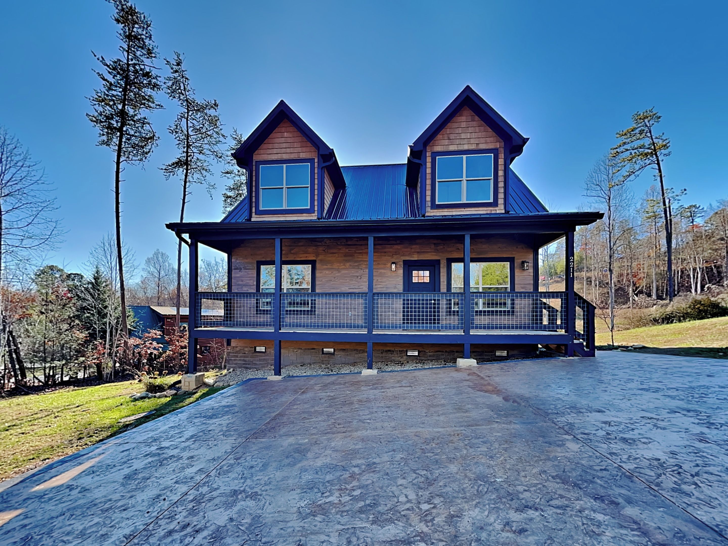 A two-story house with a wooden exterior, a balcony, and a driveway.