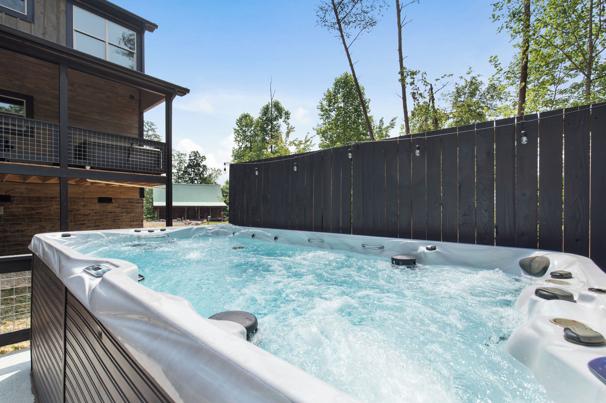 Un bain à remous avec une terrasse en bois et vue sur un immeuble doté d’un balcon.