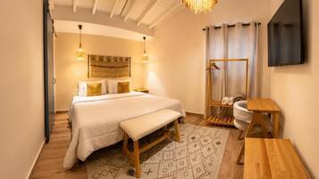 A hotel room with a bed, bedside table, bench, and a small wooden table.