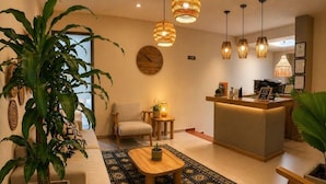 A modern living room with a sofa, a coffee table, a chair, a reception desk, and hanging pendant lights. - Luum Boutique Hotel (Medellín)