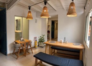 A room with a wooden dining table, two chairs, a bench, and three wicker pendant lights. - Luum Boutique Hotel (Medellín)
