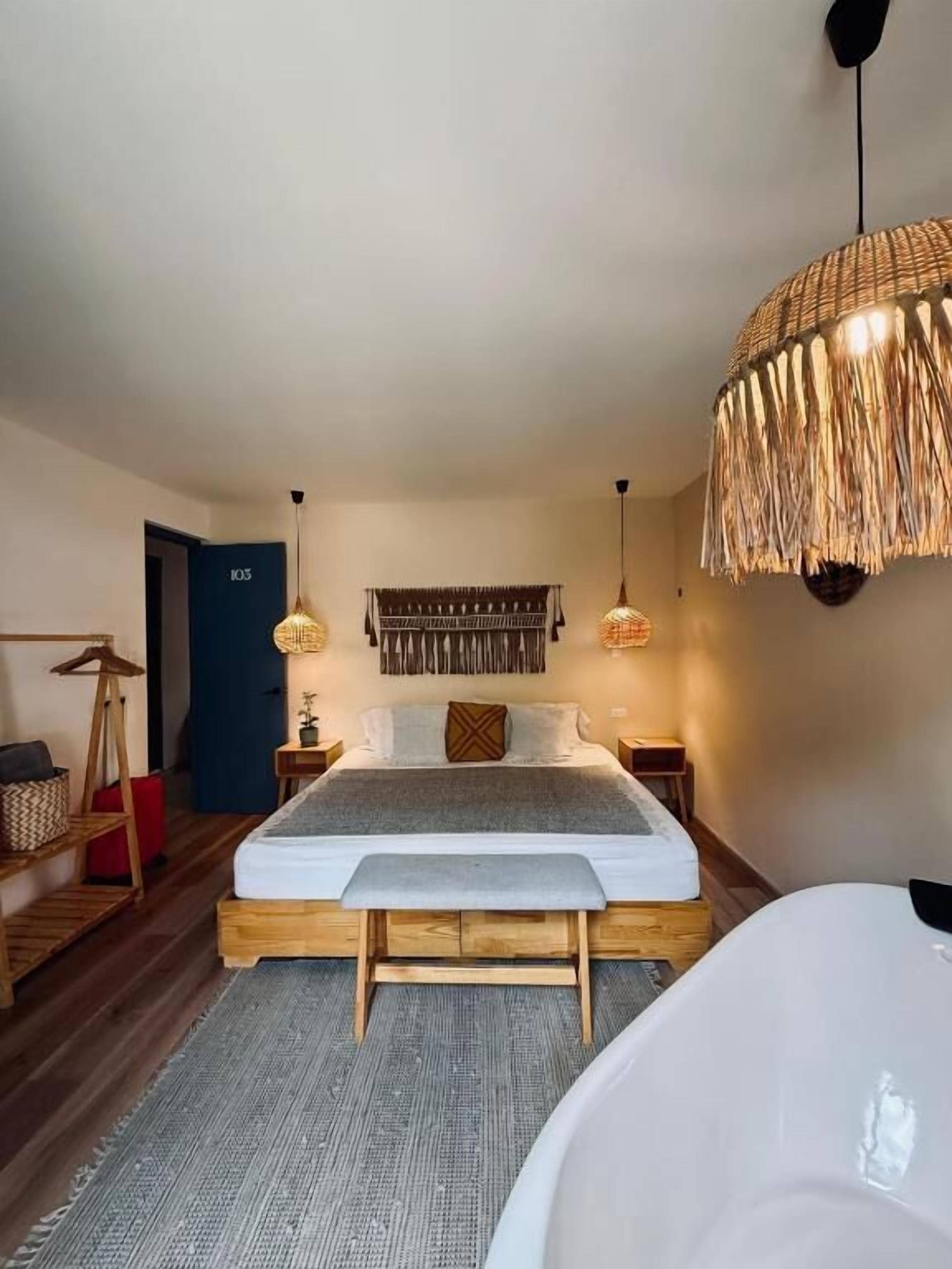 Un dormitorio con cama, mesitas de noche, lámpara colgante y una puerta con la etiqueta 'K03'.