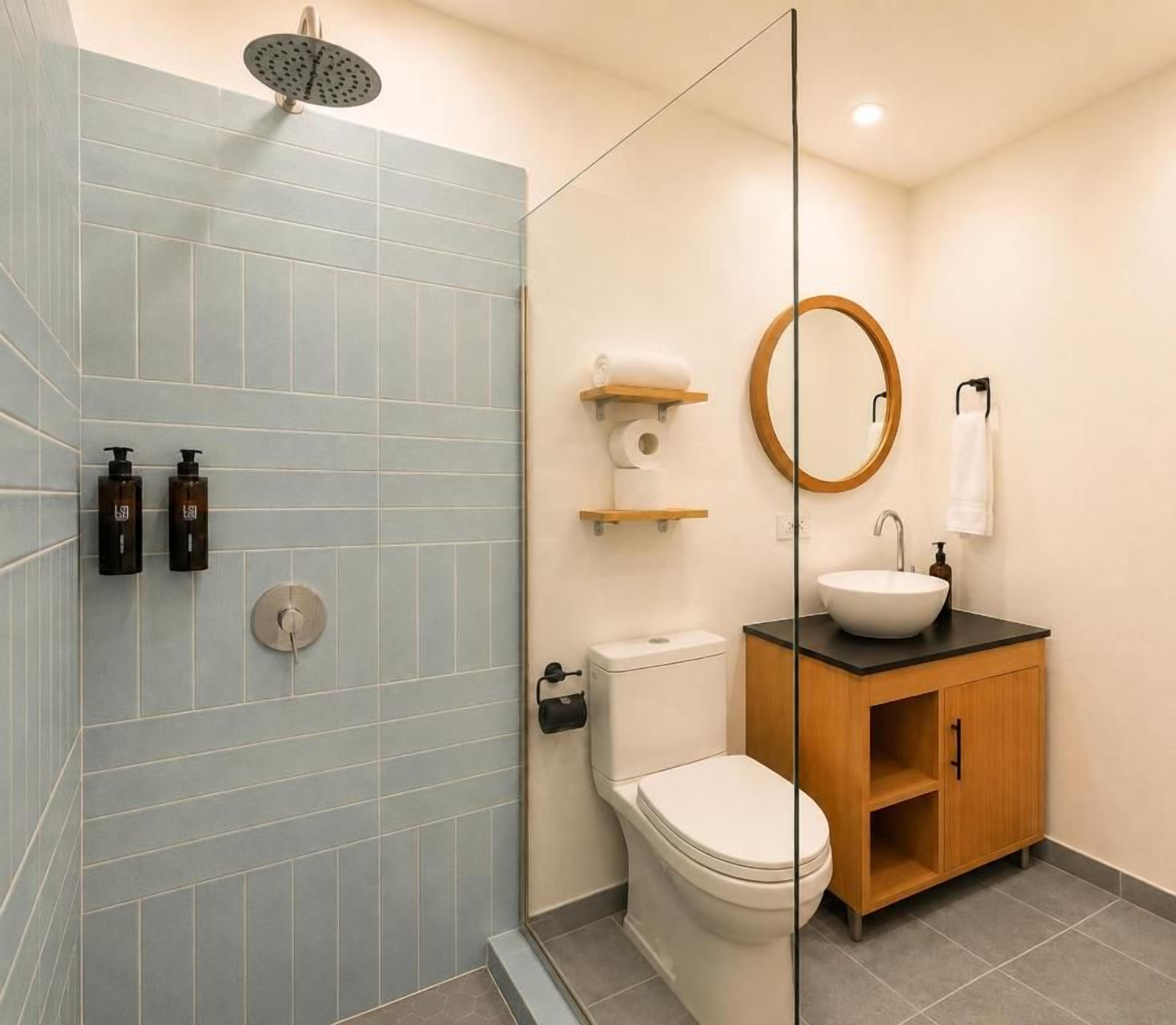 Een badkamer met een douche, toilet, wastafel en een houten kastje.