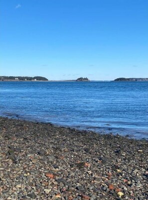 Escape to a serene coastal haven with a tranquil pebble beach and calm waters.