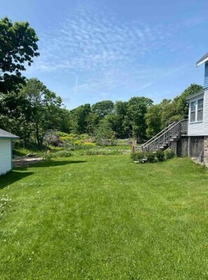 Enjoy a serene retreat in a beautifully landscaped backyard with a wooden deck and staircase.