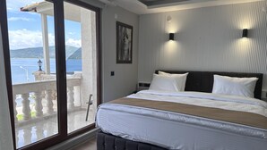 A bedroom with a large bed, a view of the sea, and a balcony with a railing. - Beyaz Köşk Hotel & Cafe (Tatvan)