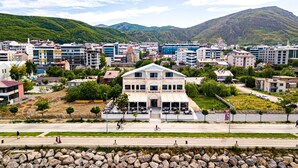 A hotel with a central courtyard, surrounded by modern buildings and a mountainous backdrop. - Beyaz Köşk Hotel & Cafe (Tatvan)