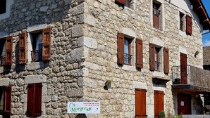 Un bâtiment en pierre doté de nombreuses fenêtres et d’une enseigne indiquant « Location de gîtes ».
