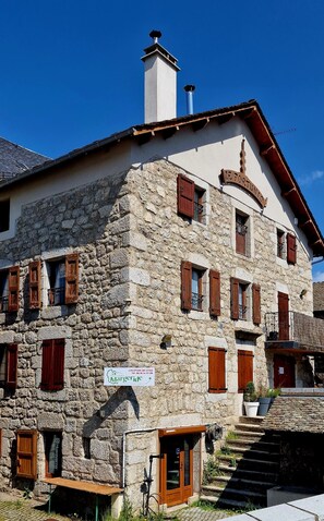 Ein Steinhaus mit zahlreichen Fenstern und einem Schild mit der Aufschrift 'Location de Gites'.