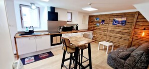 A compact kitchen with a wooden countertop, a sink, and a dining area with a table and chairs.