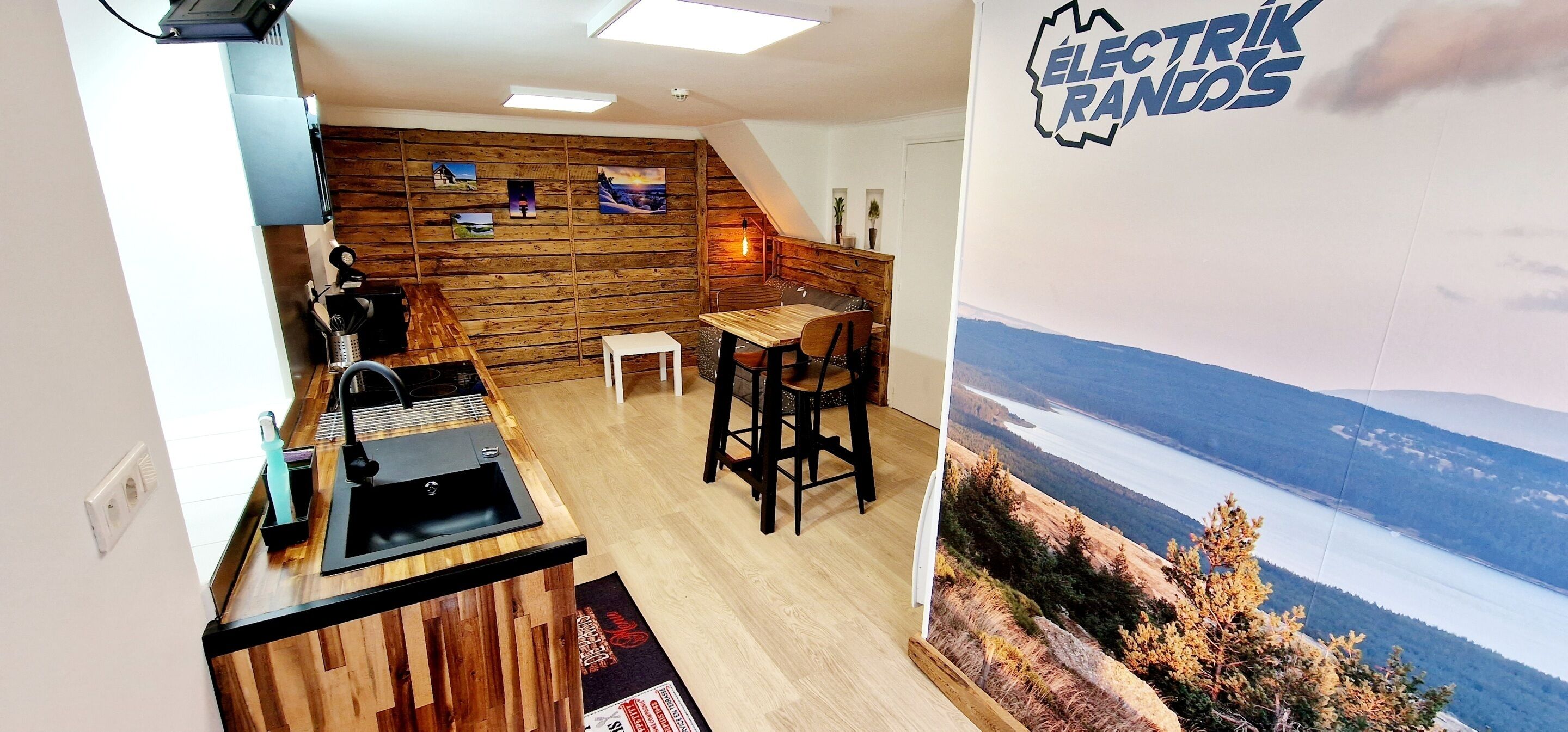 Une cuisine avec un mur en bois, un évier et un coin bar avec des tabourets.