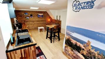 Une cuisine avec un mur en bois, un évier et un coin bar avec des tabourets.