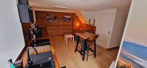Eine kompakte Küche mit einer Holzwand, einem Esstisch mit zwei Stühlen und einer weißen Tür.