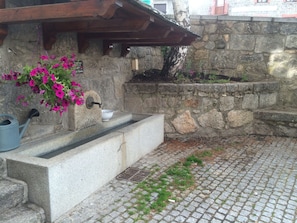 A stone wall with a water feature and a flower pot.