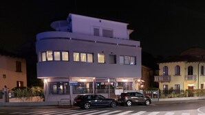 Un bâtiment moderne à la façade incurvée, doté de nombreuses fenêtres et d’une entrée protégée par un portail.